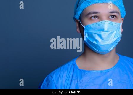 portrait rapproché d'un chirurgien de médecin caucasien, dans un costume stérile, masque, regarde loin. Sur un fond bleu. Salle d'opération. Chirurgie. Portrait d'un document Banque D'Images