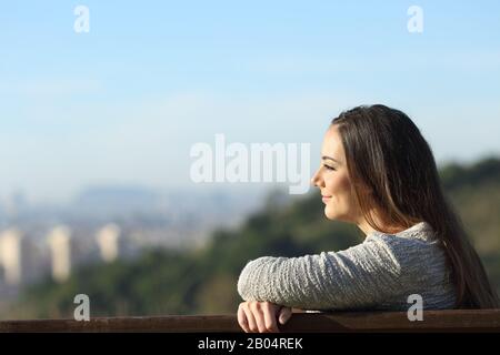 Vue latérale portrait d'une femme satisfaite contemplant des vues assis sur un banc Banque D'Images