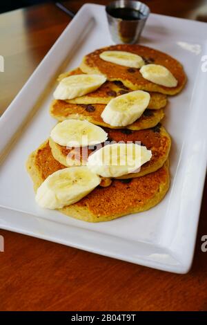 Plateau de crêpes végétaliennes à puce au chocolat avec tranches de bananes fraîches Banque D'Images