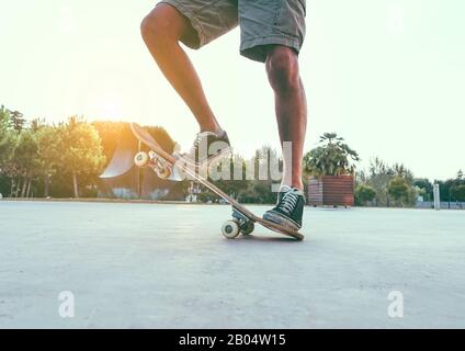 Jambes de l'homme avec planche à roulettes au coucher du soleil en plein air - Skater debout sur son long-board - concept de sport extrême - foyer principal sur la chaussure droite - filtre Vsco Banque D'Images
