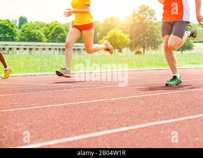 Coureurs athlètes en train de s'entraîner sur une piste de course athlétique - jeunes en plein air pour la compétition de défi - gros plan sur les jambes avec contre-éclairage Banque D'Images