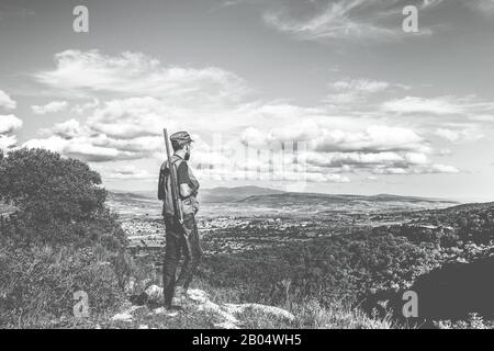Hunter jeune homme debout sur la haute montagne pendant la période de chasse - Bearded gars attendant de tirer avec vue panoramique magnifique arrière-plan - chasse Banque D'Images
