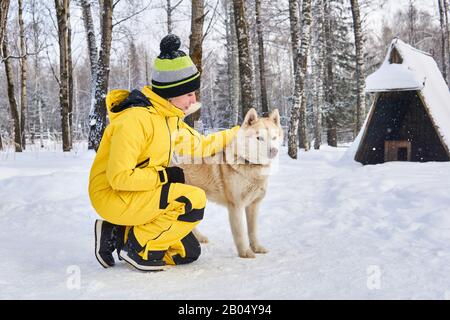 la jeune femme communique avec un chien husky dans la forêt hivernale Banque D'Images