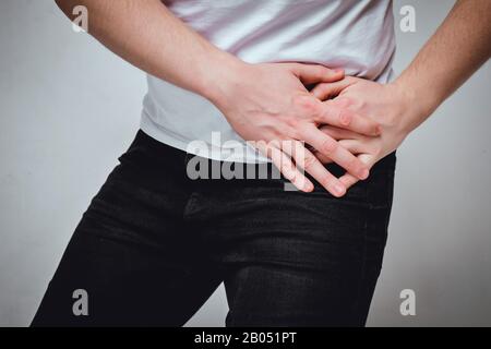 Un homme dans un T-shirt blanc souffre de douleur dans son côté gauche. Le concept de problèmes avec un ulcère d'estomac, gastrite, rate. Tons. Gros plan. Banque D'Images