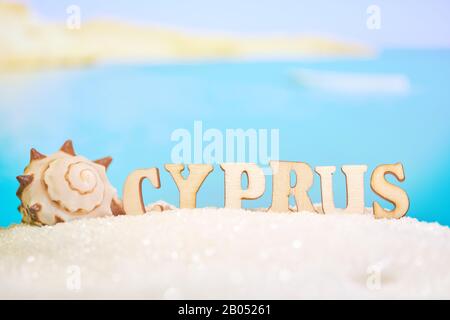 Plage abstraite sable seashell sur un fond de mer flou avec bateau et lettres. Chypre est l'une des stations balnéaires les plus populaires au monde. Gros plan. Banque D'Images
