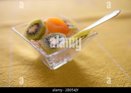 Dessert avec fromage cottage, kiwi et abricot séché dans un bol en verre sur la table Banque D'Images