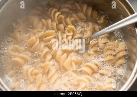 Pâtes à grains entiers dans une casserole avec eau bouillante et cuillère. Cuisiner des aliments sains Banque D'Images