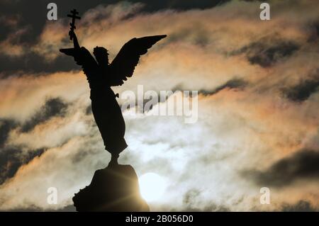 Tallinn, Estonie - 01.05.2020: Silhouette d'un ange avec une croix dans sa main sur un fond de ciel et de soleil spectaculaires. Fragment du Monument Merma Banque D'Images