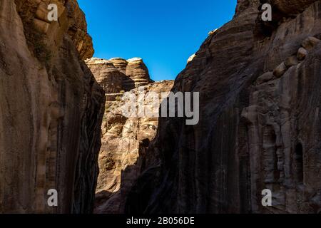 Gorge naturelle à couper le souffle appelée Al-Siq, sculptée dans les falaises rouges par le flux d'eau, le complexe de la ville antique de Petra et l'attraction touristique, Royaume hachémite de Jordanie. Jour d'hiver ensoleillé, ciel sans nuages Banque D'Images