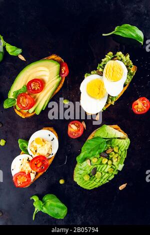 Toasts de patate douce avec avocat, œufs durs, tomates et graines de sésame sur fond sombre. Concept de repas sain. Cuisine propre, plats du Pescetarian, vue sur le dessus Banque D'Images