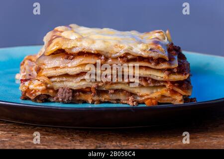 partie de lasagnes fraîches sur une plaque bleue Banque D'Images