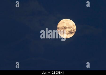 Pleine lune derrière des nuages moelleux. Banque D'Images