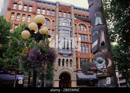 USA, WASHINGTON, SEATTLE, PLACE PIONNIÈRE, TLINGIT TOTEM, BÂTIMENT PIONNIER EN ARRIÈRE-PLAN Banque D'Images