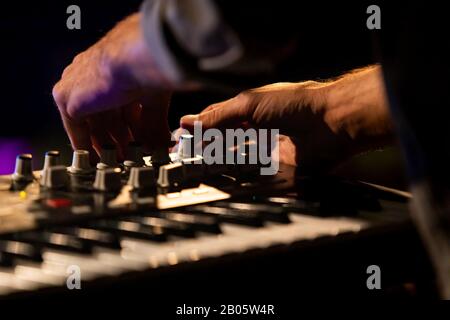 Une mise au point sélective rapprochée a tourné sur les mains d'un homme jouant un clavier électronique, tournant les cadrans pendant une nuit fixée à un festival multiculturel Banque D'Images