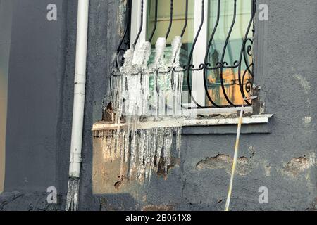 treillis recouvert de glace sur la fenêtre d'une ancienne maison avec revêtement décollement Banque D'Images