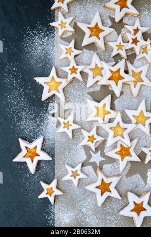 Cookies Au Citron Et À La Tarte Faits Maison. Les biscuits au curd de citron et à la pêche préservent les étoiles avec du sucre glace sur parchemin et un fond d'ardoise Banque D'Images