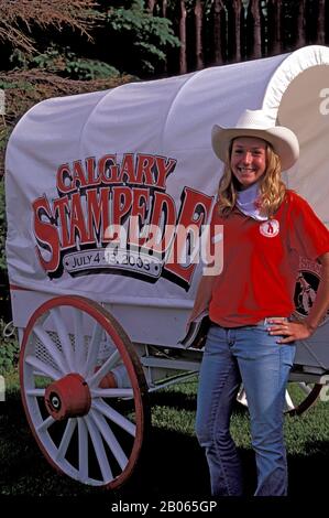 CANADA, ALBERTA, CALGARY, CALGARY STAMPEDE, FILLE QUI SE POSE DEVANT UN WAGON Banque D'Images