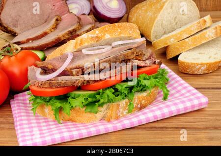 Sandwich à salade de bœuf rôti avec ingrédients sur fond de bois Banque D'Images