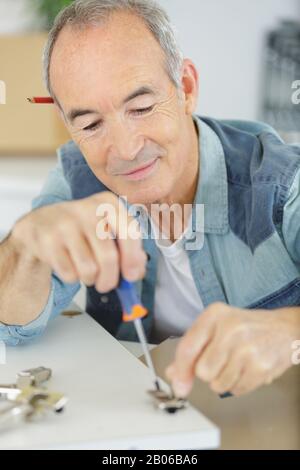 un homme senior visse quelque chose Banque D'Images