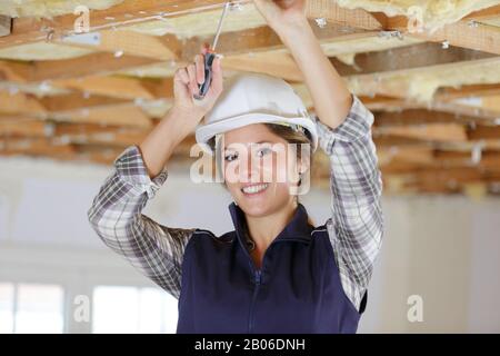 Female electrician l'installation de lumières au plafond Banque D'Images