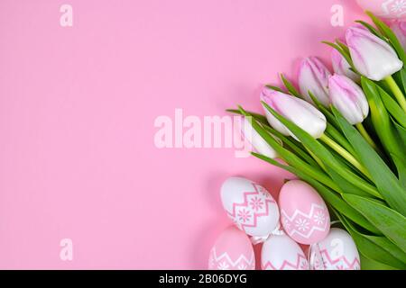 Bouquet de fleurs de printemps de tulipes blanches et de mignons œufs de pâques dans un coin de fond rose clair avec espace de copie vierge Banque D'Images