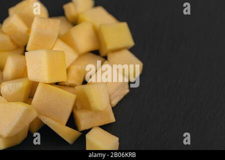 Citrouille, morceaux de courgettes coupés en tranches de cube sur fond noir. Banque D'Images