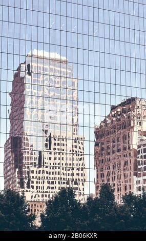 Les vieux bâtiments de New York se reflètent dans les fenêtres d'un gratte-ciel moderne, avec un fond urbain coloré. Banque D'Images