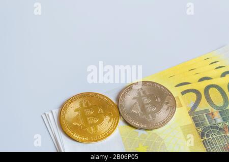 Pièces de monnaie doré sur fond de 200 billets en papier Euro. Le concept de commerce et la valeur des crypto-monnaies et des euros . Banque D'Images