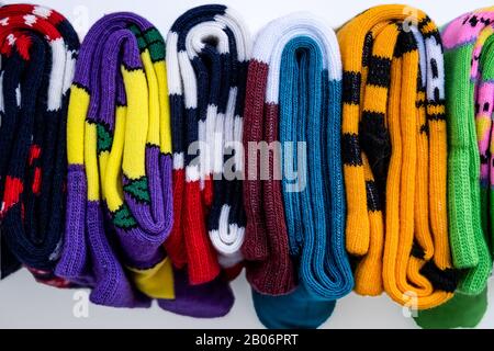 Plusieurs chaussettes en coton colorées se roulent sur fond blanc. Banque D'Images