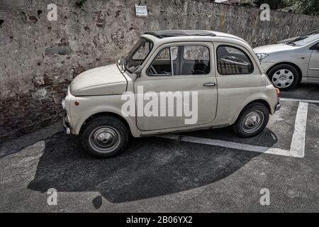 Ancienne Fiat 500 voiture devant un vieux mur de pierre en Italie Pise Toscane Banque D'Images