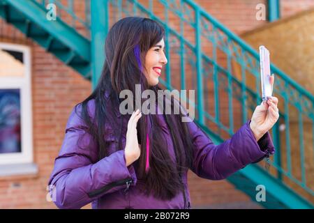 Technologies, concept urbain et populaire - Jolie fille avec de longs cheveux colorés prend un selfie sur le toit. Banque D'Images
