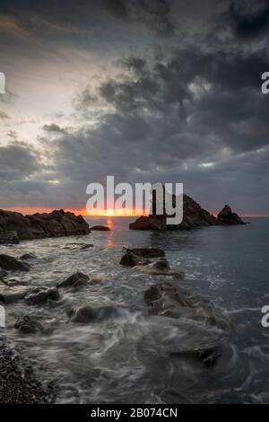 Image Seascape au lever du soleil des vagues blanches qui se précipitent sur la plage rocheuse appelée Galeazza, Province d'Imperia, Ligurie, nord-ouest de l'Italie Banque D'Images