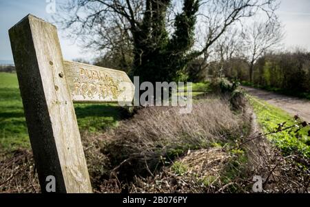 Panneau de sentier public de campagne anglaise. Un panneau de crocheté recouvert de mousse et de lichen dirigeant les randonneurs sur leur itinéraire. Banque D'Images