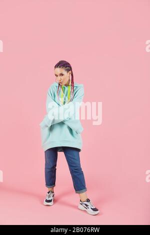 Jeune danseuse vêtue de vêtements surdimensionnés sur fond de studio isolé rose Banque D'Images