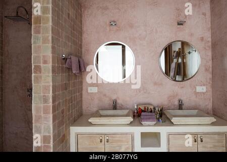 Salle de bains aux tons roses avec miroirs circulaires Banque D'Images