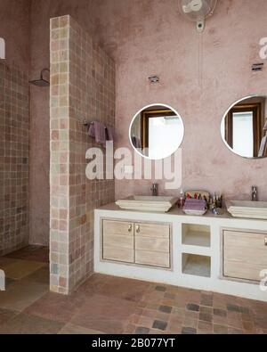 Salle de bains aux tons roses avec miroirs circulaires Banque D'Images