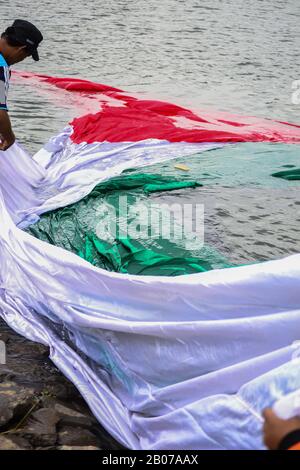 Tangerang, Indonésie - 23 février 2013 : les hommes indonésiens se lavent et sèchent le drapeau géant palestinien au bord de la rivière à Tangerang, Indonésie Banque D'Images