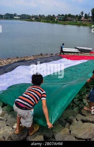 Tangerang, Indonésie - 23 février 2013 : les hommes indonésiens se lavent et sèchent le drapeau géant palestinien au bord de la rivière à Tangerang, Indonésie Banque D'Images