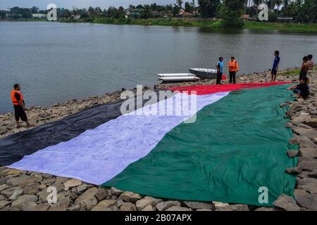 Tangerang, Indonésie - 23 février 2013 : les hommes indonésiens se lavent et sèchent le drapeau géant palestinien au bord de la rivière à Tangerang, Indonésie Banque D'Images