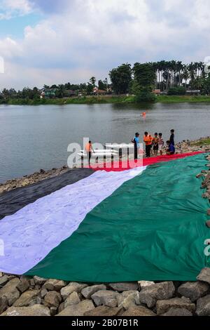 Tangerang, Indonésie - 23 février 2013 : les hommes indonésiens se lavent et sèchent le drapeau géant palestinien au bord de la rivière à Tangerang, Indonésie Banque D'Images