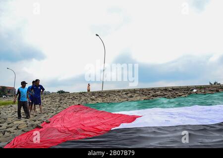 Tangerang, Indonésie - 23 février 2013 : les hommes indonésiens se lavent et sèchent le drapeau géant palestinien au bord de la rivière à Tangerang, Indonésie Banque D'Images