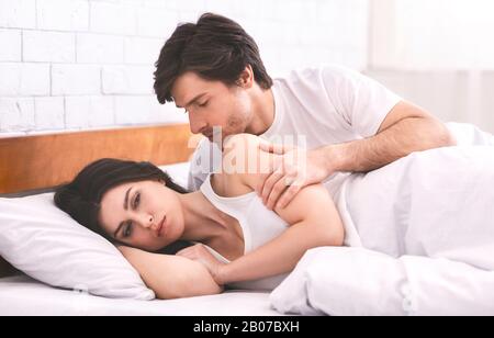 Coupable homme essayant de communiquer avec sa femme incriminée au lit Banque D'Images