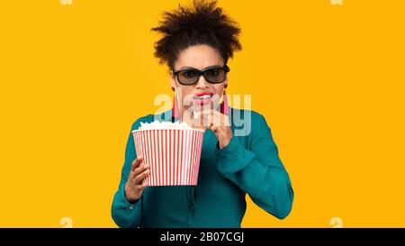 Une jeune fille afro choquée dans des lunettes en relief qui regardaient le film Banque D'Images