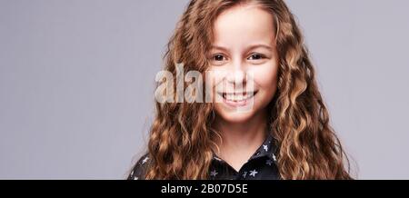 Femme au sourire. Cheveux longs. Belle jeune fille studio portrait. Coupe adorable. Arrière-plan gris avec espace de copie. Style de vie positif. Banque D'Images