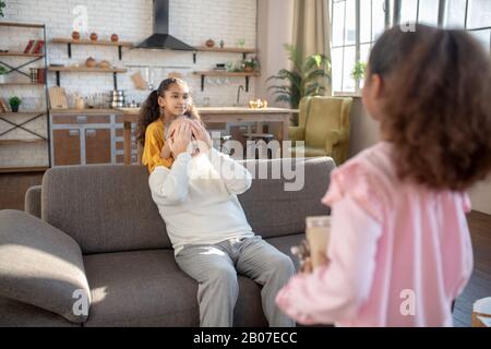 Jolie fille à peau foncée tenant un cadeau d'anniversaire pour son grand-père Banque D'Images