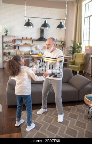 Fille à peau foncée en Jean dansant avec son grand-père Banque D'Images