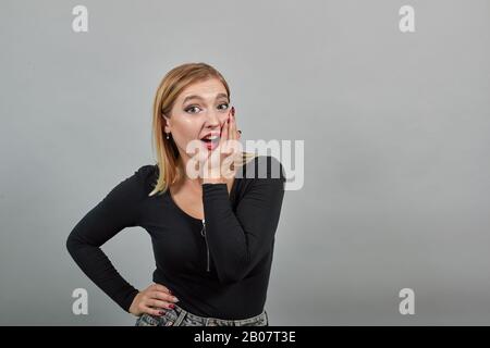 fille dans la veste noire surprise femme réagit positivement à la surprise Banque D'Images