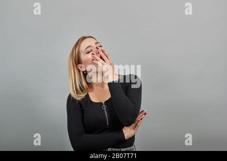 fille dans la veste noire fatiguée femme yawns, veut dormir, couvre la bouche avec la main Banque D'Images