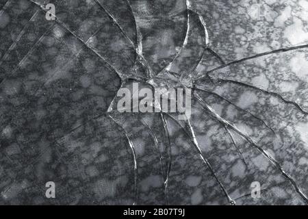 Texture abstraite d'une feuille de verre cassée sur fond de pierre sombre Banque D'Images