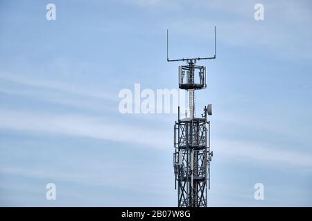 Gros plan du mât en réseau avec station de base pour les communications mobiles contre le ciel bleu avec nuages. Vu en Allemagne en février Banque D'Images